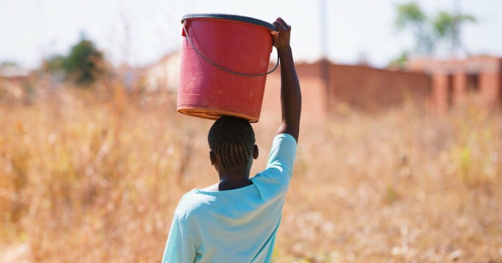 An African man carrying a bucket of clean water