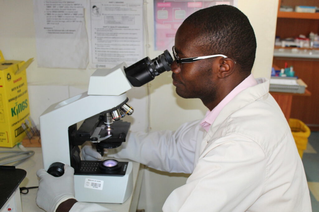 beacon of hope health worker looking through microscope
