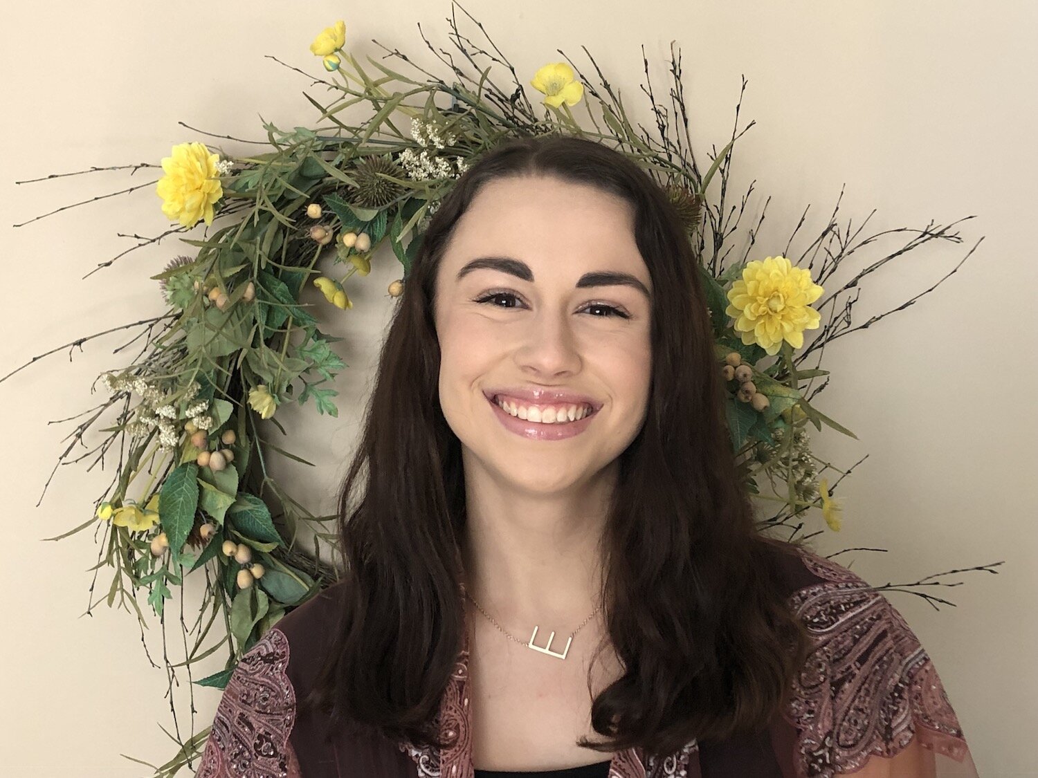 elena walker smiles in front of a wreath of flowers