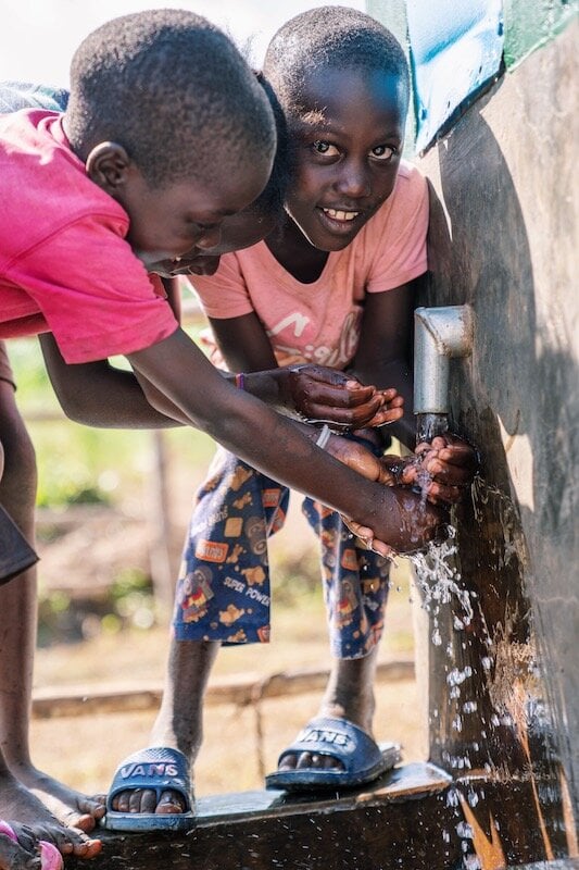 children smiling while running hands under water