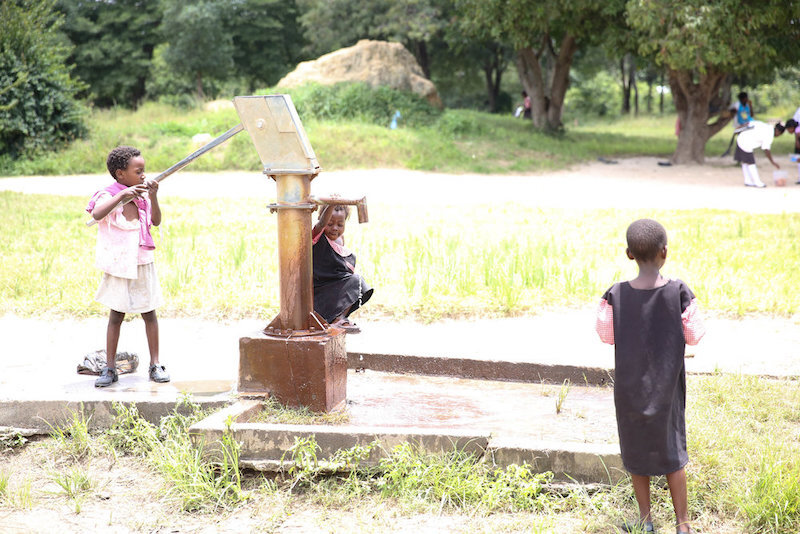 this is a borehole well. one person pumps the handle in order to draw the water out.