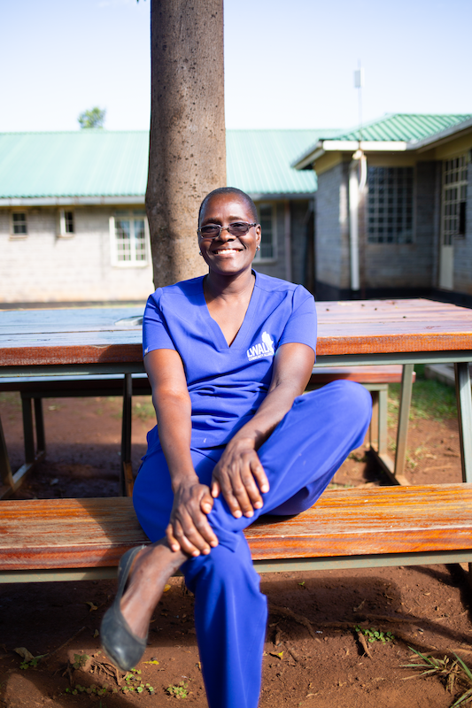 community health worker sits at a bench, smiling