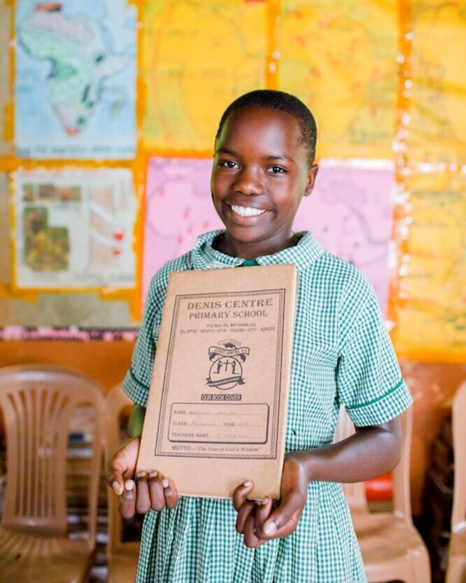 African student holding her notebook and smiling in a classroom