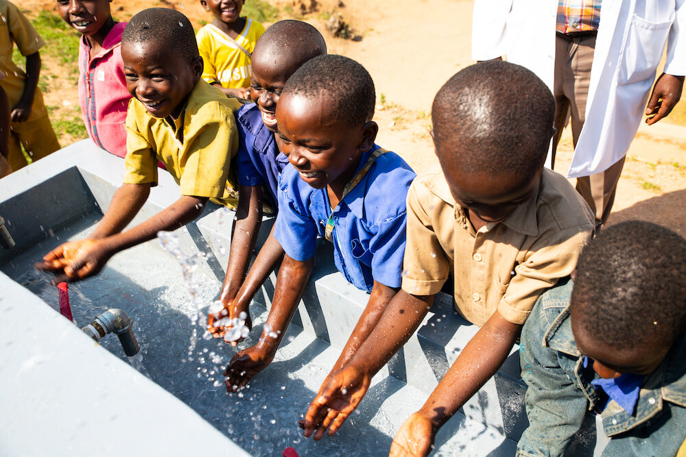 african schoolchildren drawing water from their school’s new clean water facility