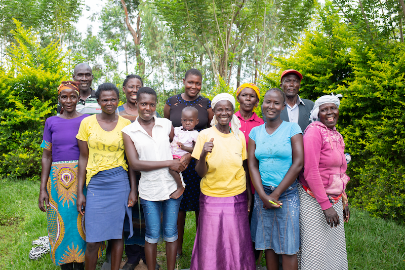 an hiv support group in kenya stands together smiling at the camera