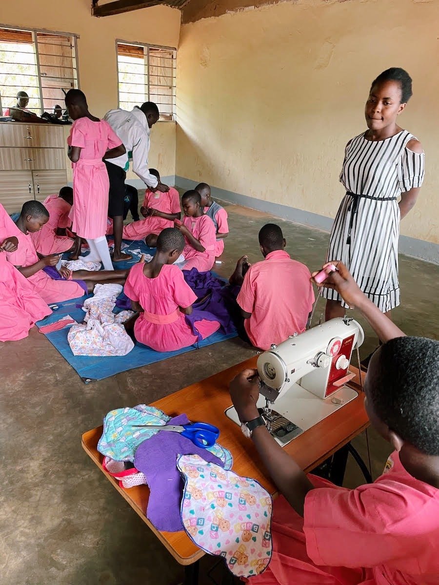 multiple girls learning how to sew reusable menstrual pads in a classroom