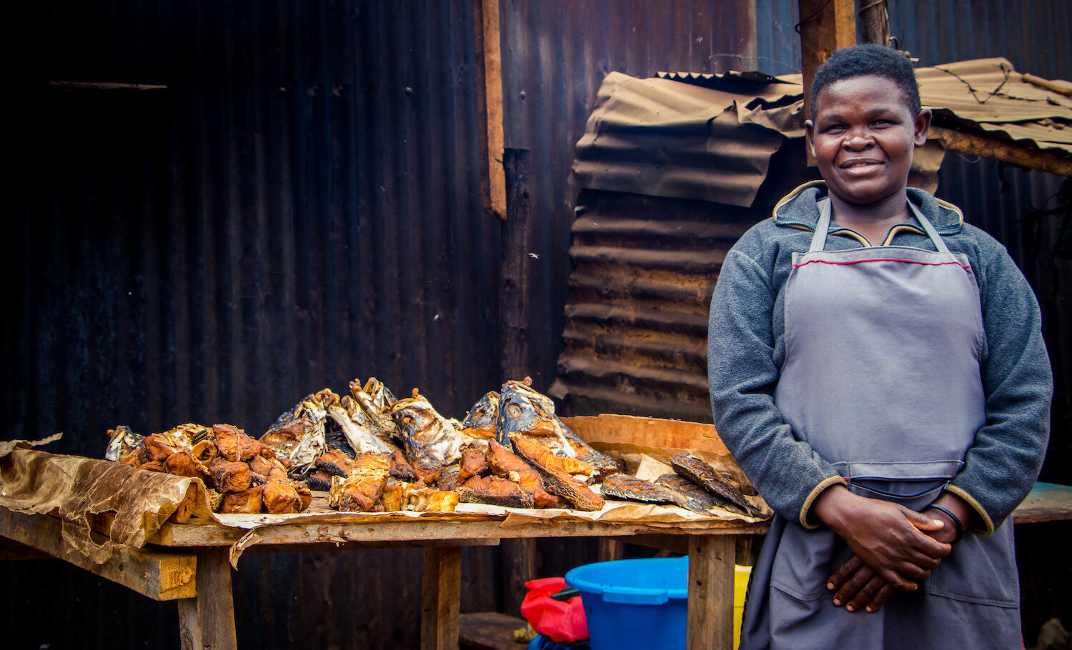 woman standing in front of cooked fish on a table