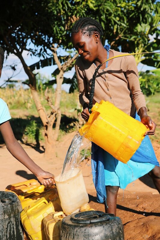 women filling water buckets