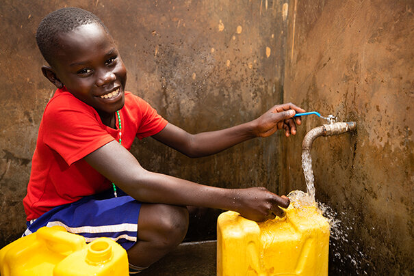 ephraim draws clean water from the new well at his school