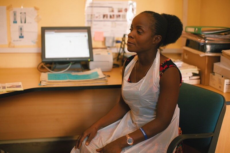 health worker sits at a desk, staring off to the side