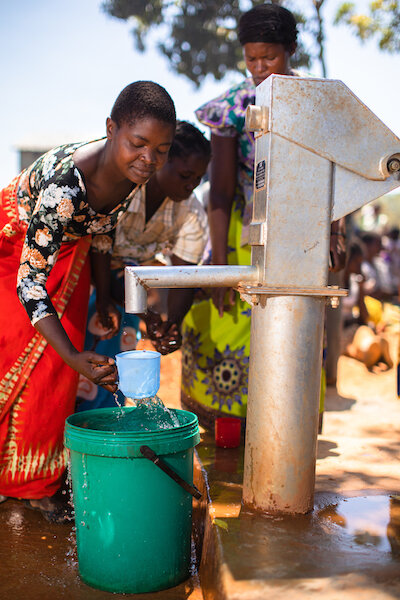 two women from the chifenthe village draw clean water from their new clean water well