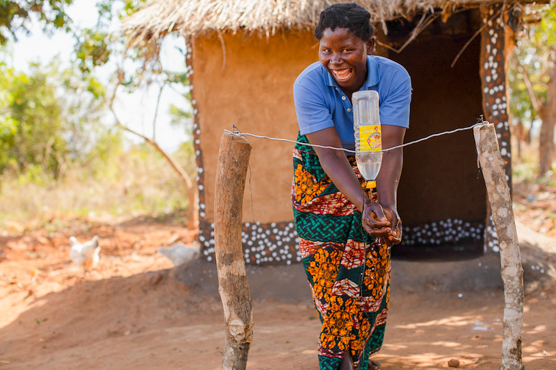 woman in malawi washing her hands using a tippy tap