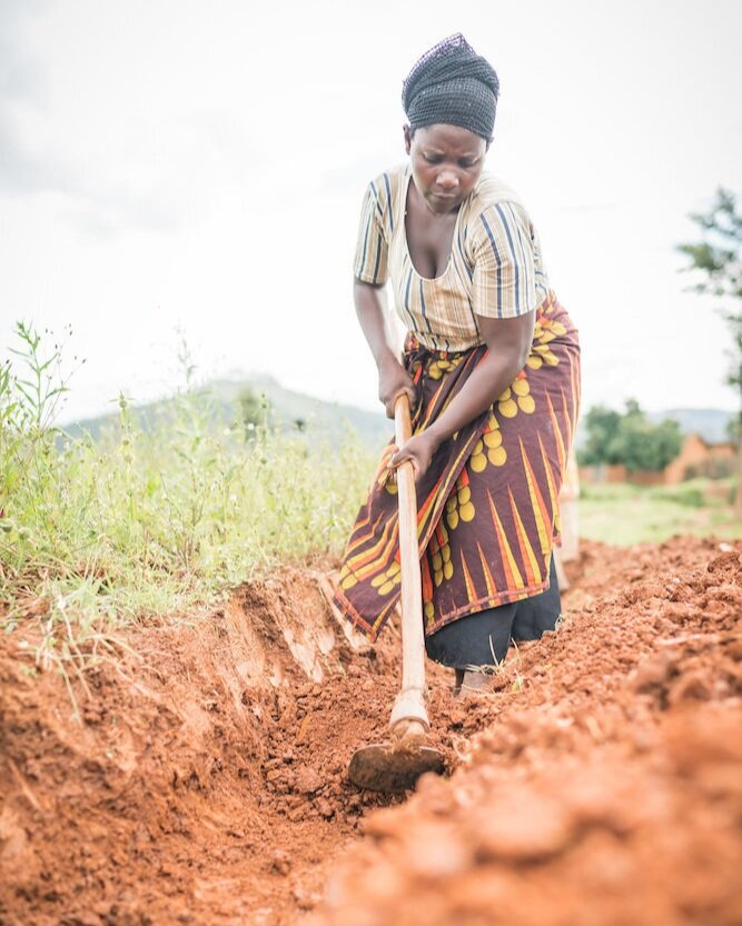 Migisha’s mother digging a trench for the water pipeline in her village