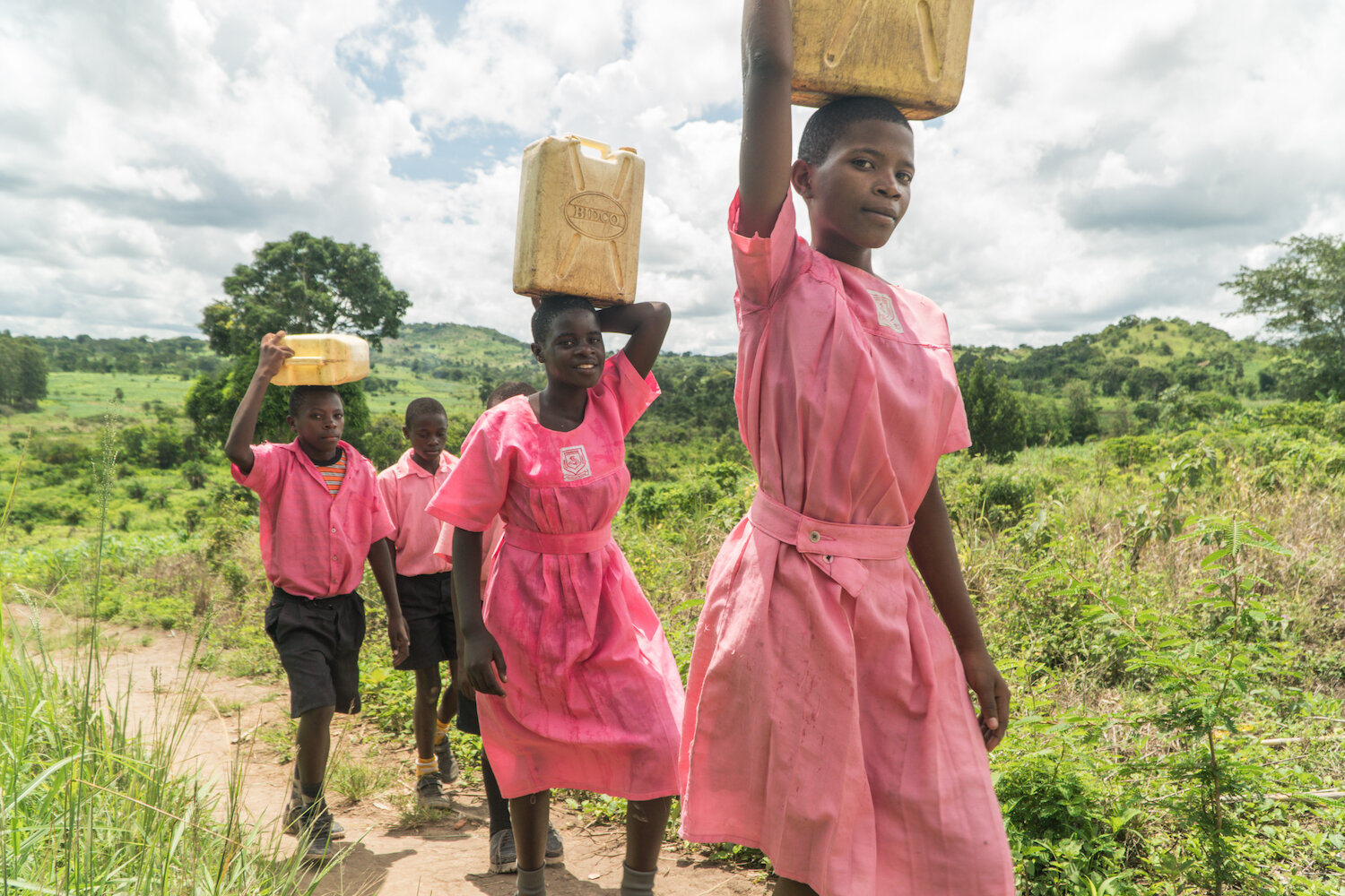 Pact beneficiary students hauling jerrycans with water