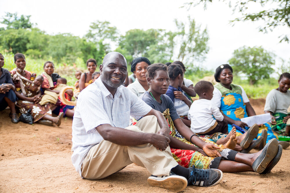 Jimmy sitting with community members in Neno, Malawi