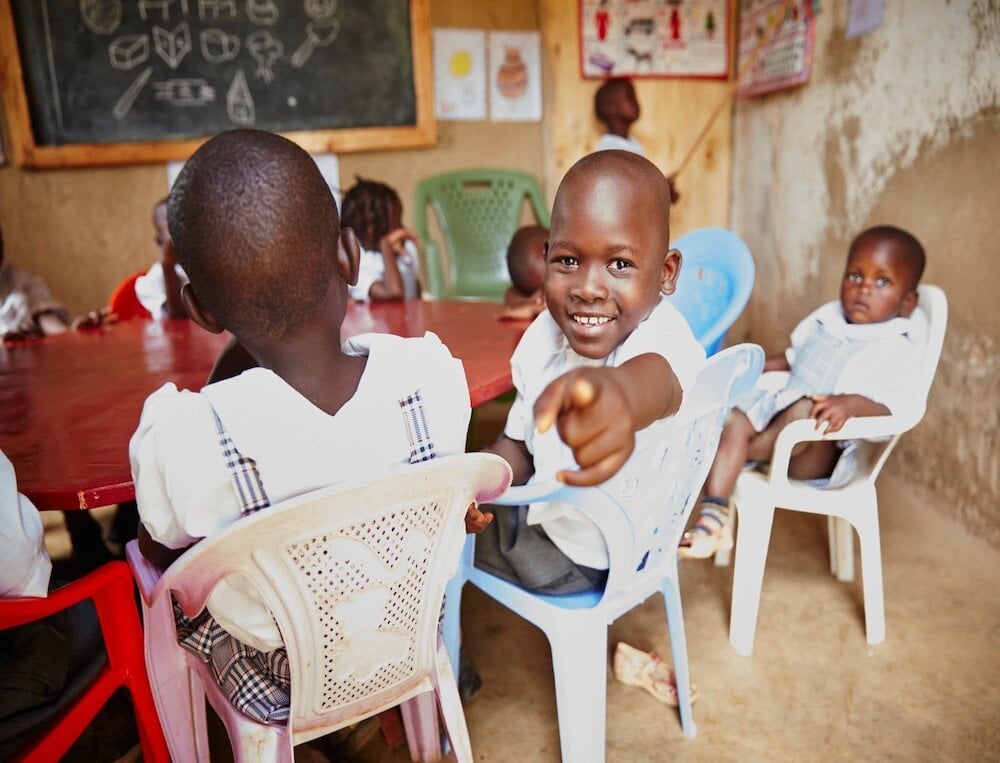 child sitting at table, pointing and smiling