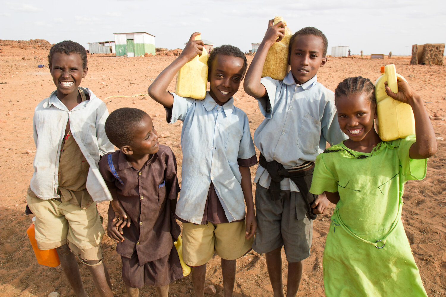 group of african school children carrying water jugs