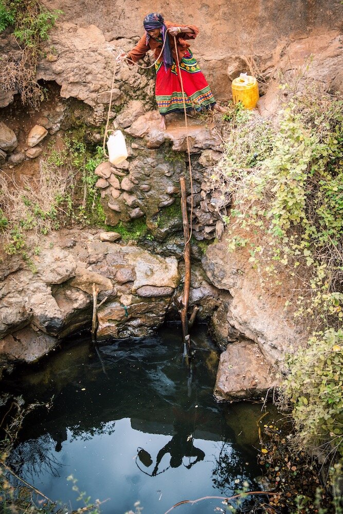 african woman drawing water from an unsafe water source