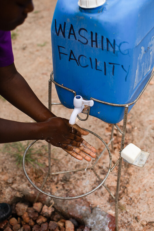 schoolgirl uses her school’s sanitation station to wash her hands