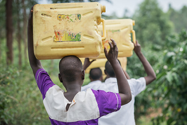 girl wearing school uniform carrying clean water in a jerrycan on her head