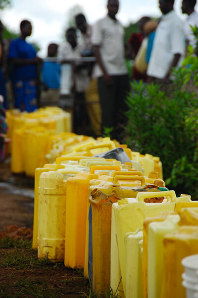 jerrycans lined up containing clean water, thanks to water projects in africa