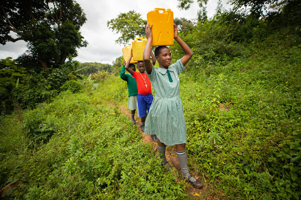 schoolchildren in africa carry jerrycans with clean water on their heads