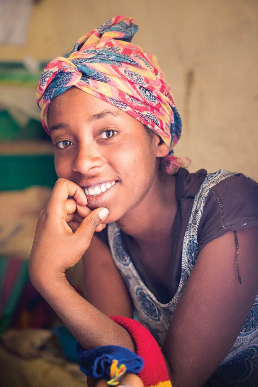 african girl with headscarf smiles at camera