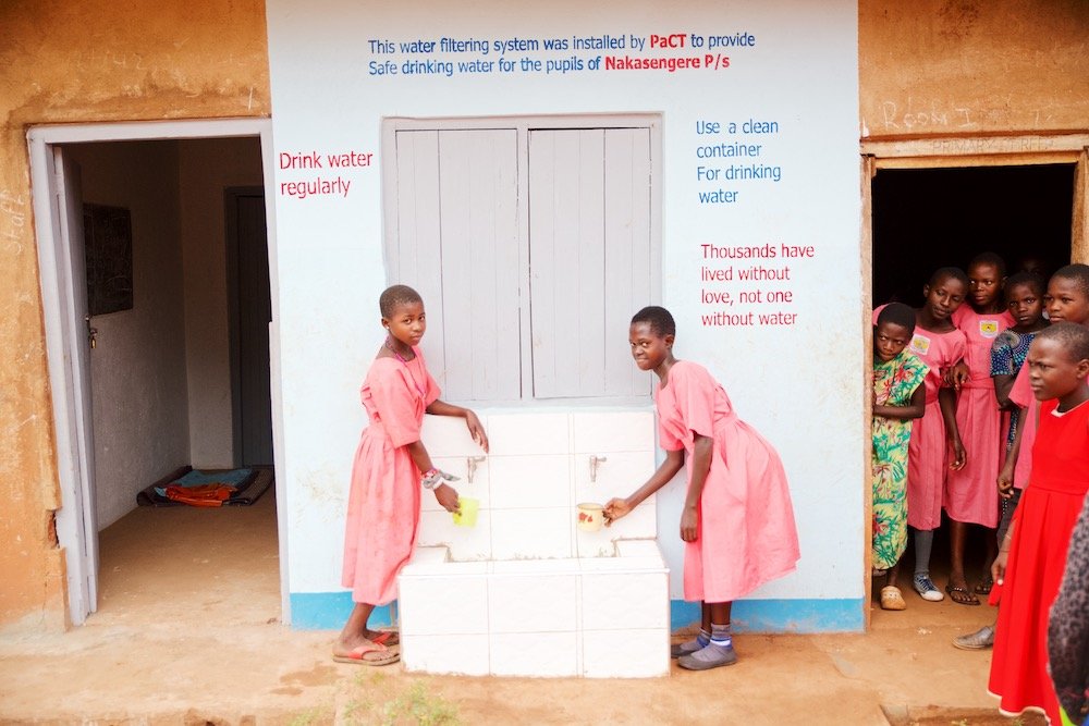 two girls getting clean water from water filtering system