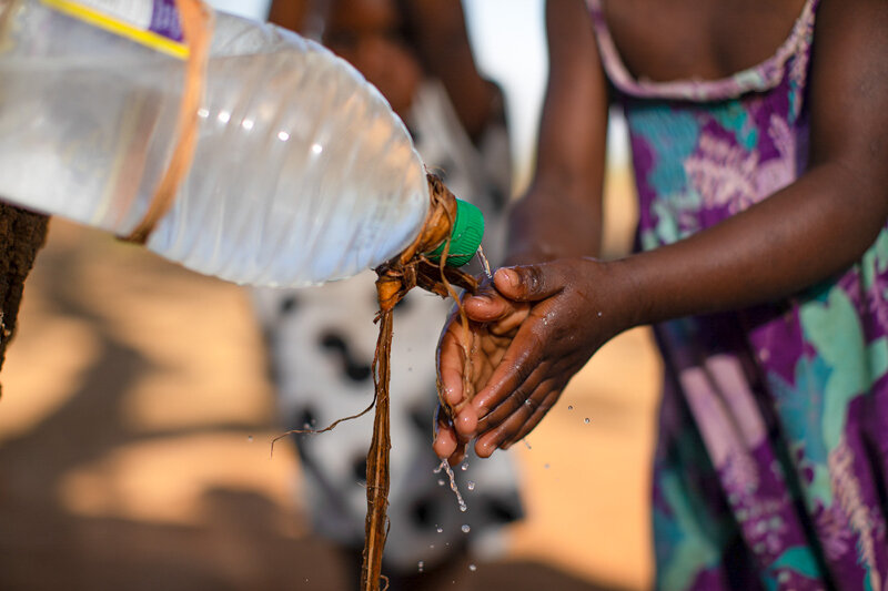 girl in malawi washing hands using a tippy tap