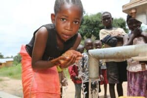 A young African girl drinking from a well