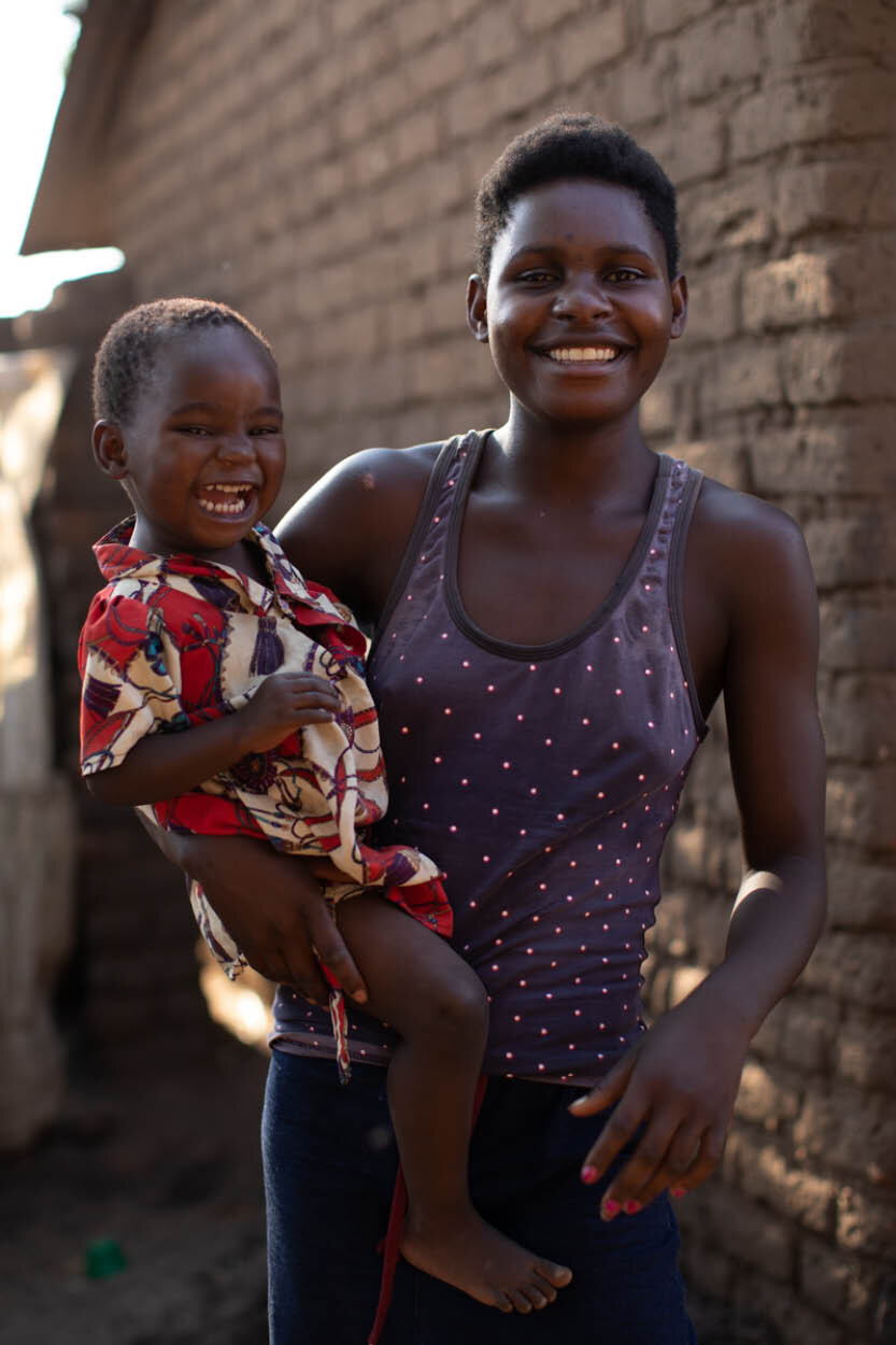 african woman holds her child as they both smile and laugh