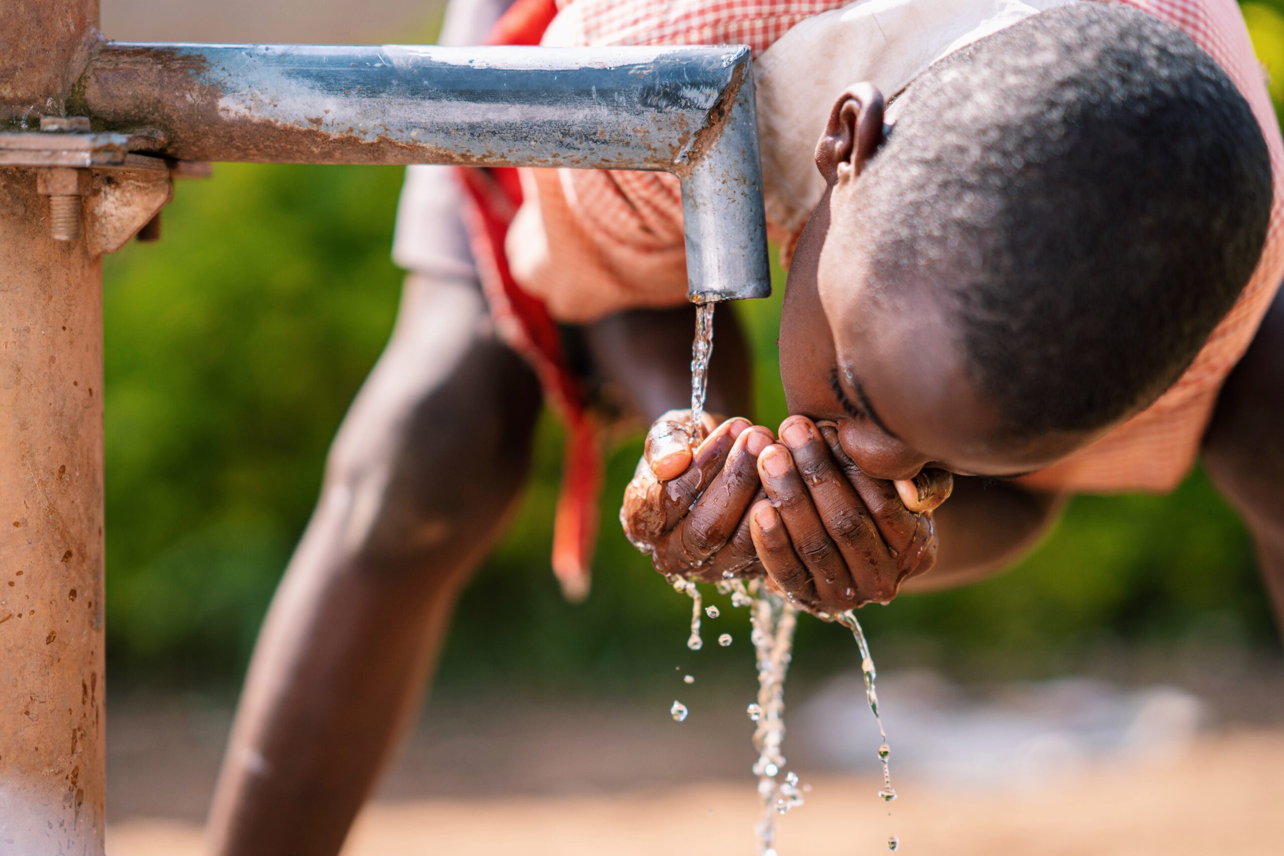 Child drinking water with hands
